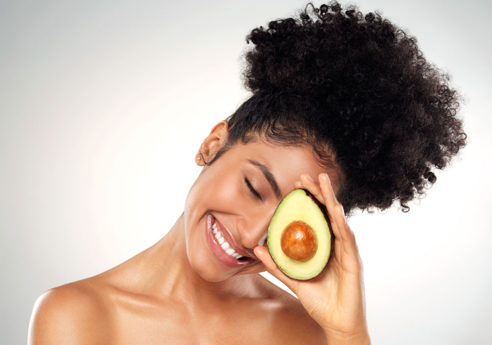 woman with curly hair holding avocado