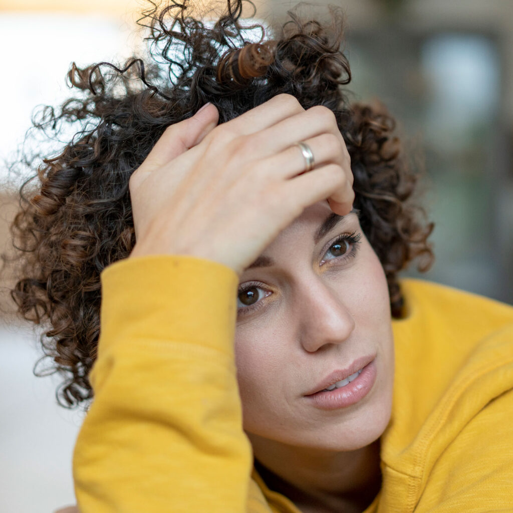 woman with curly hair with hand on head